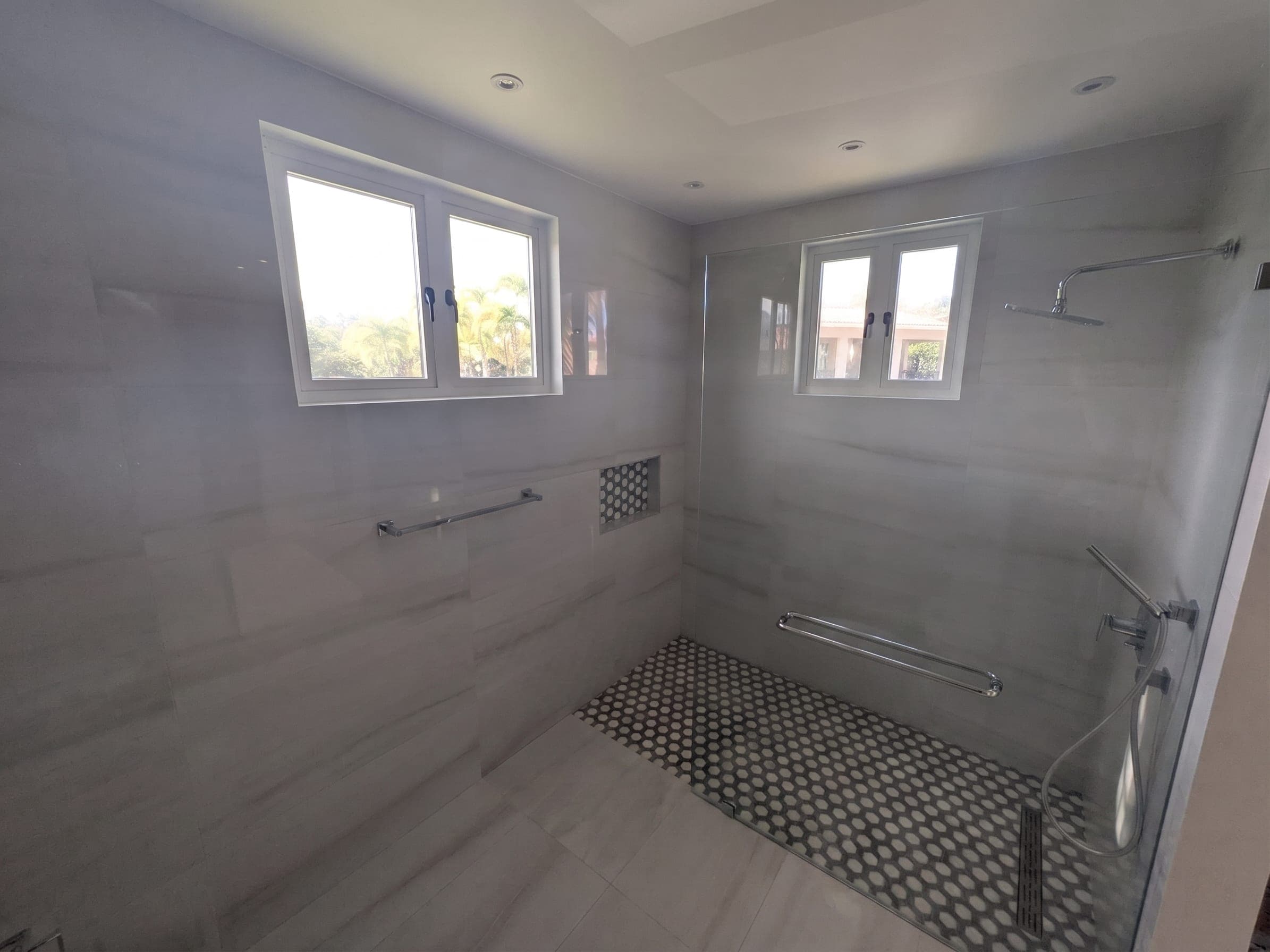 Primary bathroom shower with hex tile floor detail