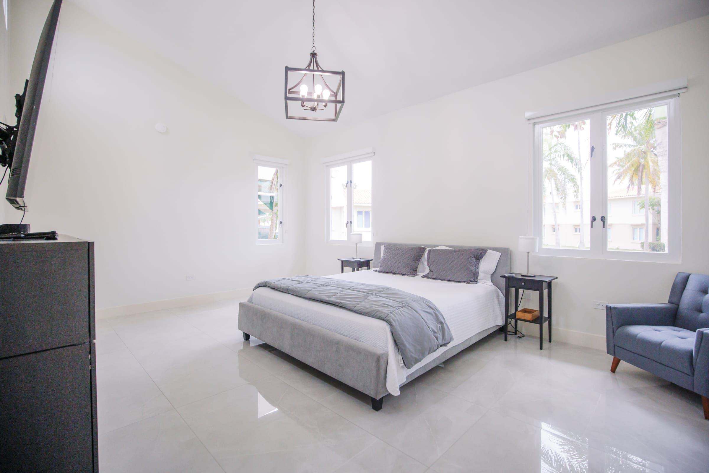 Primary bedroom with upholstered bed, accent chair, and pendant light