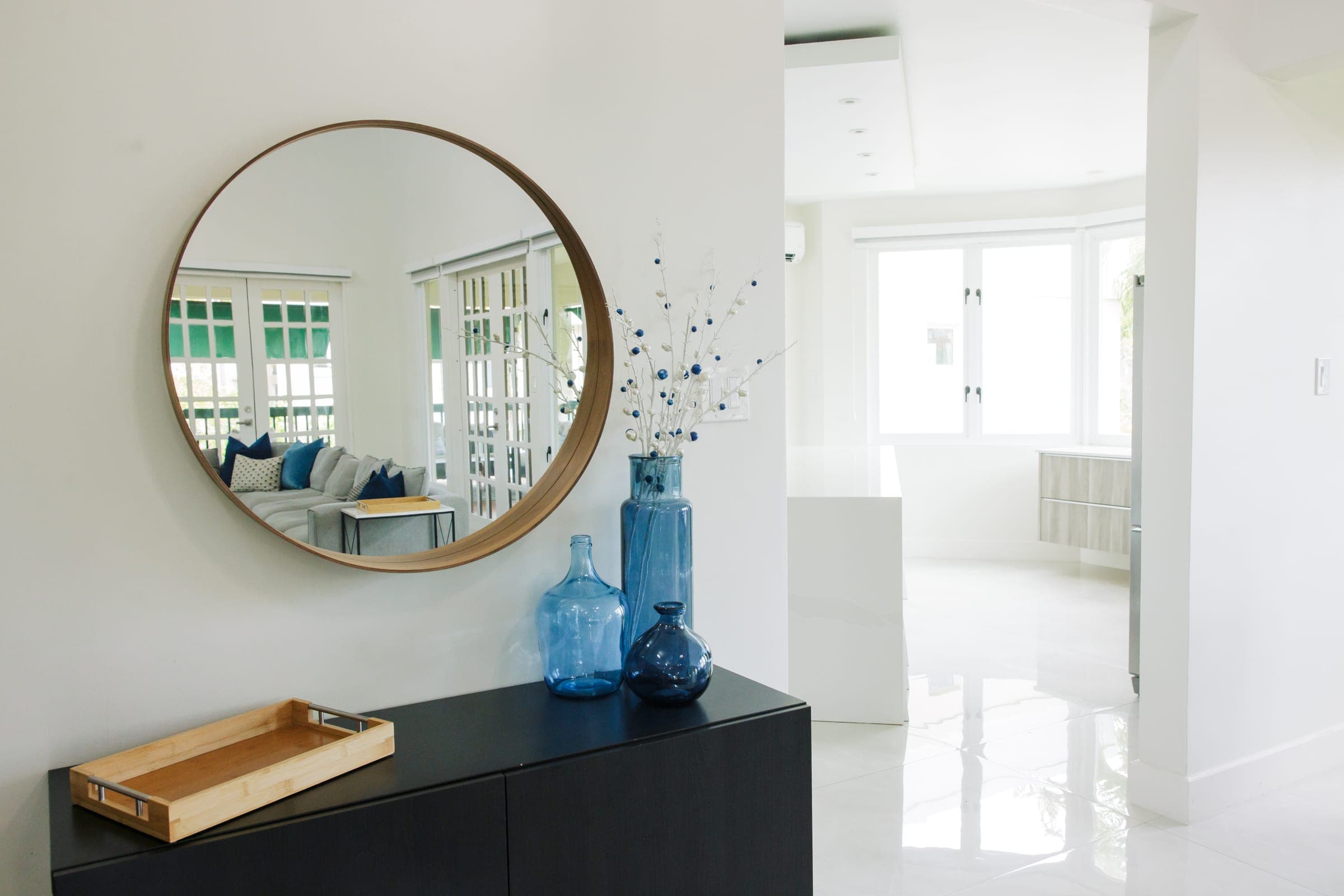 Entry foyer with floating console, round mirror, and view into the living area