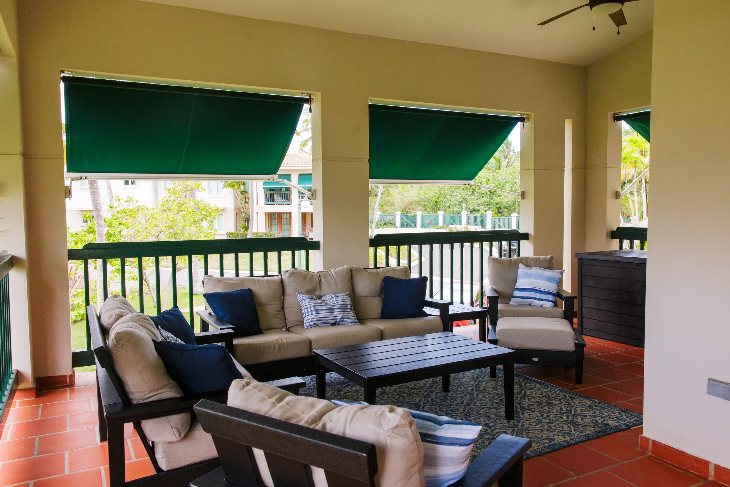 Porch lounge with sofa and armchairs framed by green awnings and views of the lakes