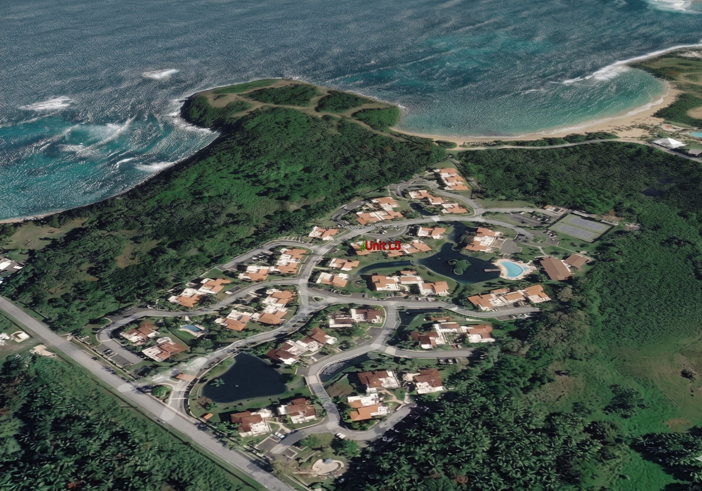 Aerial view of Lakeside Villas community set against the Vega Alta coastline, with the headland and beach approach visible